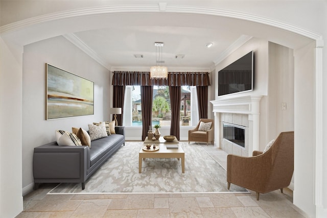 living area with baseboards, arched walkways, crown molding, and a tile fireplace