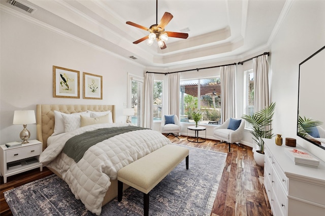 bedroom featuring wood finished floors, visible vents, a ceiling fan, ornamental molding, and a raised ceiling