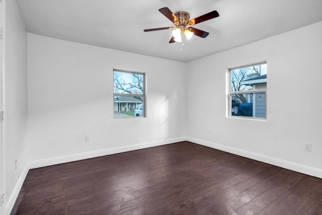 spare room with dark wood-type flooring, ceiling fan, and a healthy amount of sunlight