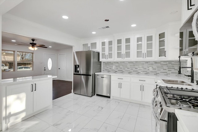 kitchen with appliances with stainless steel finishes, white cabinetry, sink, decorative backsplash, and crown molding