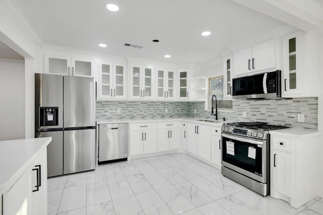 kitchen featuring appliances with stainless steel finishes, sink, white cabinets, decorative backsplash, and light stone counters