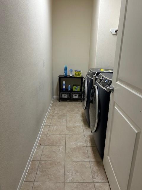 clothes washing area with light tile patterned flooring and washing machine and dryer