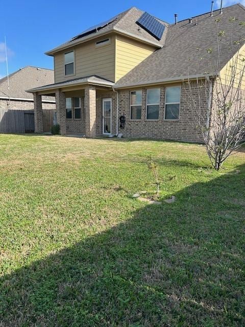 rear view of property with a yard and solar panels