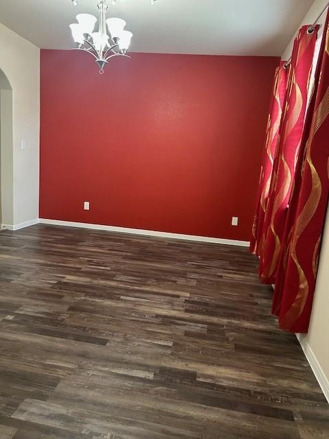 spare room with dark hardwood / wood-style floors and a notable chandelier