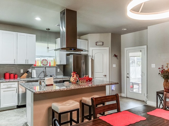 kitchen featuring a center island, island range hood, white cabinets, and stainless steel refrigerator