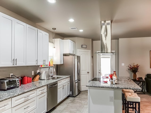 kitchen with decorative light fixtures, sink, white cabinets, stainless steel dishwasher, and light stone counters