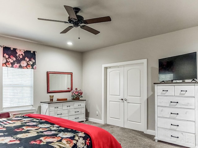 bedroom featuring light carpet, ceiling fan, and a closet