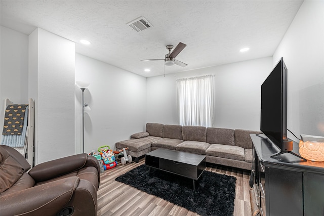 living room featuring hardwood / wood-style floors, a textured ceiling, and ceiling fan