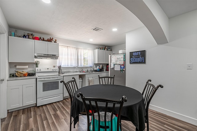 kitchen with white electric range, white cabinetry, sink, stainless steel fridge, and dark hardwood / wood-style flooring