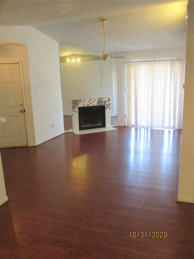 unfurnished living room featuring lofted ceiling, a fireplace, dark hardwood / wood-style floors, and ceiling fan