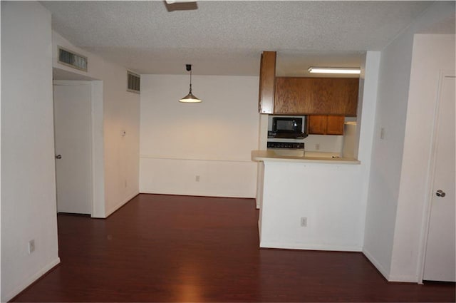 kitchen featuring refrigerator, hanging light fixtures, a textured ceiling, dark hardwood / wood-style flooring, and kitchen peninsula