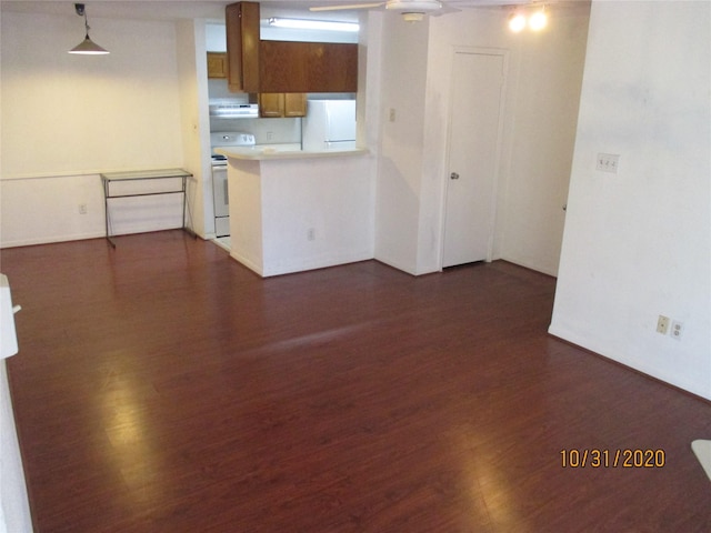 kitchen with pendant lighting, white appliances, dark hardwood / wood-style flooring, and kitchen peninsula