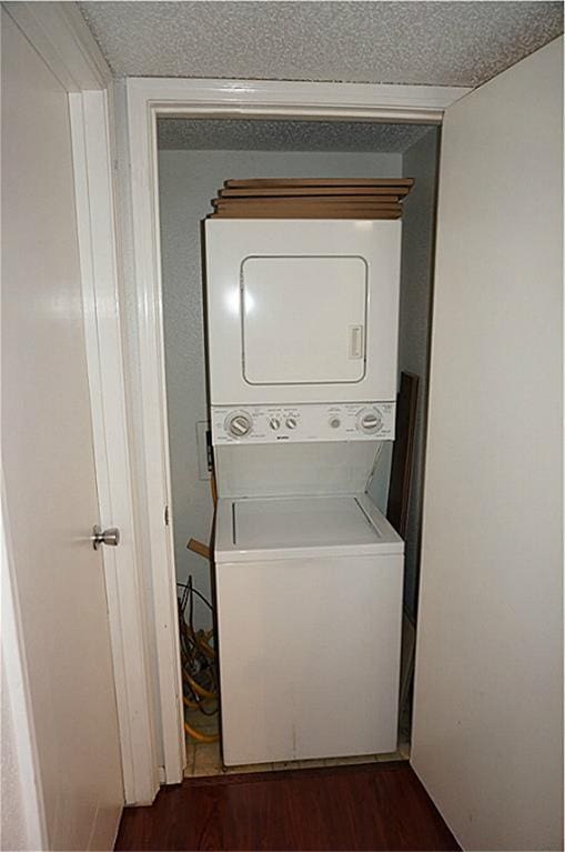 laundry room with dark hardwood / wood-style flooring, a textured ceiling, and stacked washer / dryer