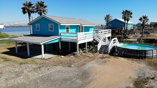 back of house featuring a swimming pool side deck with water view