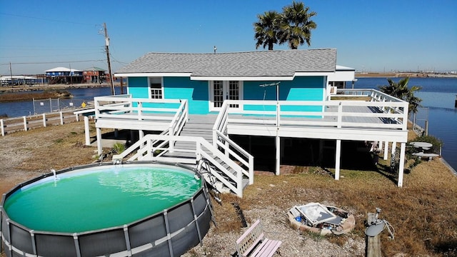 rear view of house with a pool side deck with water view