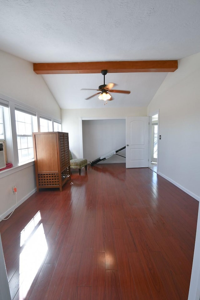 unfurnished living room featuring vaulted ceiling with beams, dark wood-type flooring, and a textured ceiling