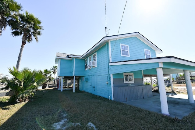 rear view of property featuring a carport, a yard, and cooling unit