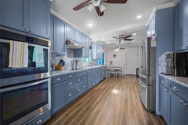 kitchen featuring stainless steel appliances, dark wood-type flooring, blue cabinets, and decorative backsplash