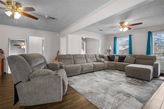 living room featuring dark wood-type flooring, ceiling fan, crown molding, and a textured ceiling