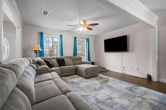 living room featuring a textured ceiling, wood-type flooring, ornamental molding, and ceiling fan