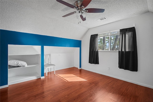 unfurnished bedroom with wood-type flooring, vaulted ceiling, ceiling fan, and a textured ceiling