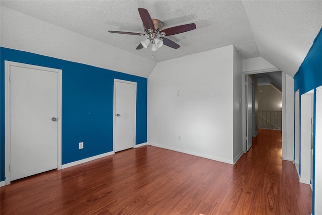 interior space featuring ceiling fan, vaulted ceiling, dark hardwood / wood-style floors, and a textured ceiling