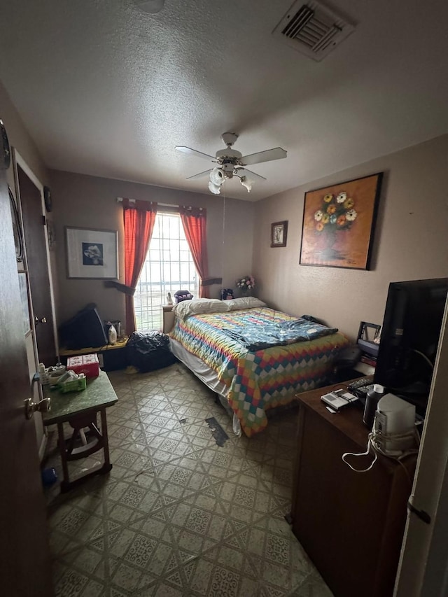 bedroom with ceiling fan and a textured ceiling