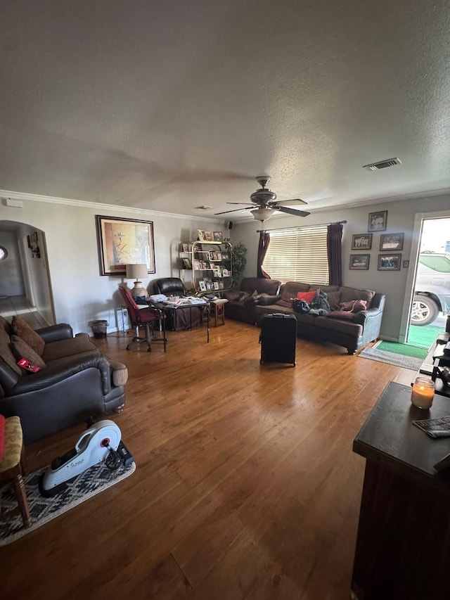 living room featuring hardwood / wood-style flooring, ceiling fan, crown molding, and a textured ceiling