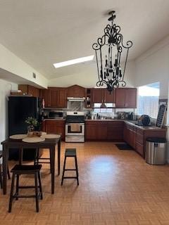 kitchen with stainless steel appliances, vaulted ceiling, hanging light fixtures, and a notable chandelier