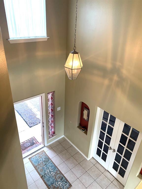 entrance foyer with a high ceiling, light tile patterned flooring, and french doors