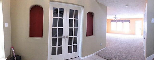 corridor with french doors, light carpet, and a textured ceiling