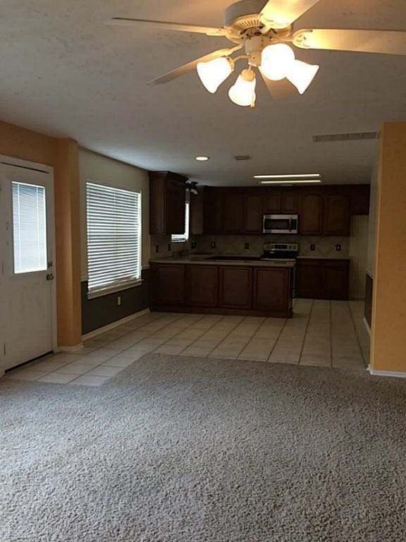 kitchen featuring ceiling fan, stainless steel appliances, dark brown cabinets, and light tile patterned floors