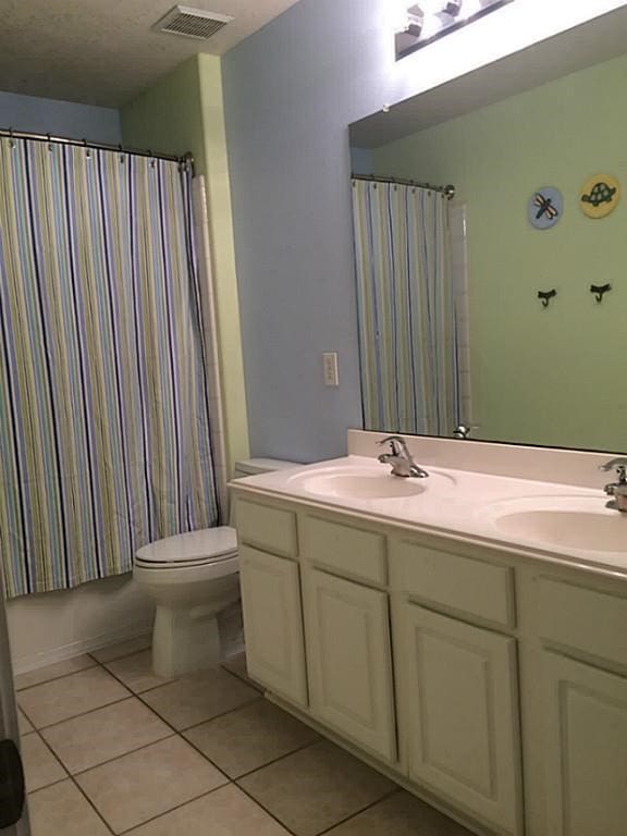 full bathroom featuring shower / bath combo with shower curtain, tile patterned floors, toilet, and vanity