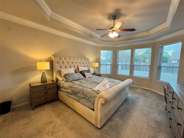 carpeted bedroom with a tray ceiling, ornamental molding, and ceiling fan