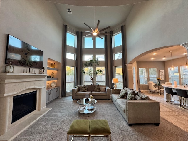 living room with built in shelves and ceiling fan