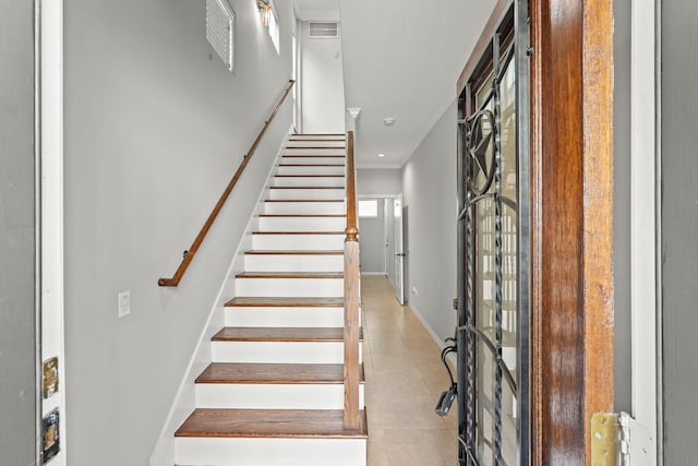 staircase with crown molding and tile patterned floors