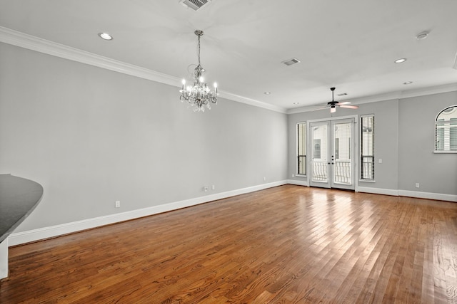 empty room with hardwood / wood-style flooring, crown molding, ceiling fan with notable chandelier, and french doors