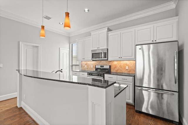 kitchen with crown molding, stainless steel appliances, white cabinets, and a center island with sink