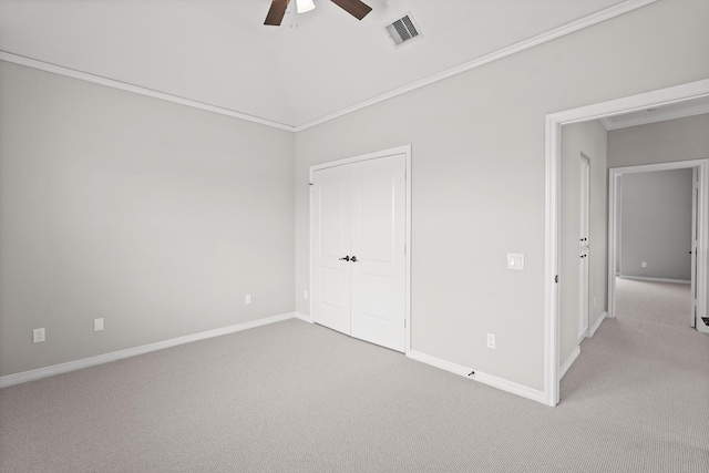 unfurnished bedroom with crown molding, light colored carpet, ceiling fan, and a closet