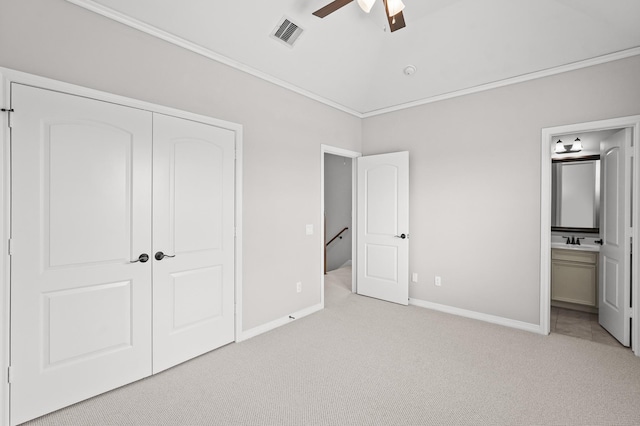 unfurnished bedroom featuring connected bathroom, crown molding, vaulted ceiling, light carpet, and a closet