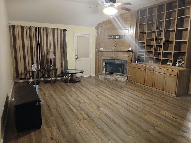 living room featuring ceiling fan, a high end fireplace, hardwood / wood-style floors, and lofted ceiling