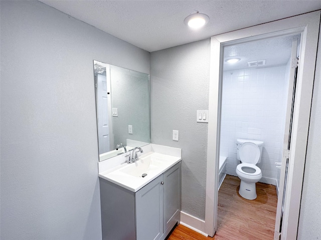 bathroom featuring hardwood / wood-style flooring, vanity, toilet, and a textured ceiling