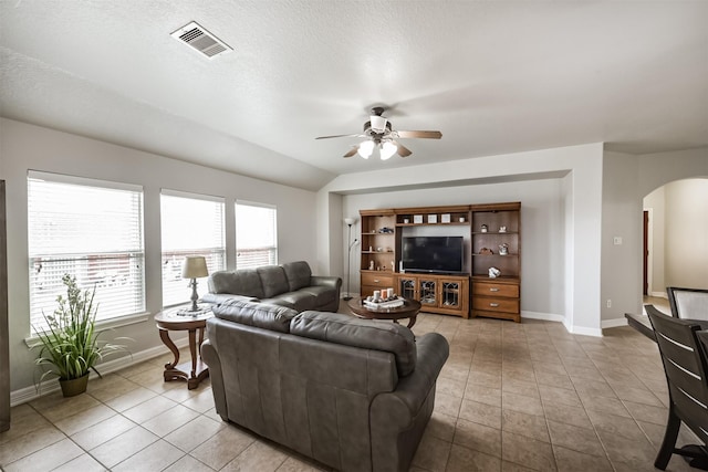 living room with a textured ceiling, vaulted ceiling, ceiling fan, and light tile patterned flooring