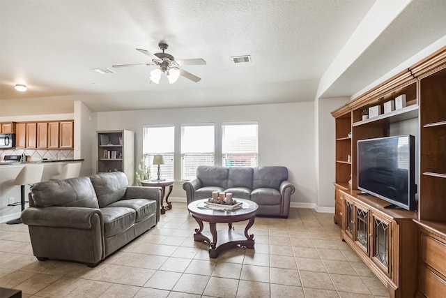 living room with ceiling fan, a textured ceiling, and light tile patterned floors