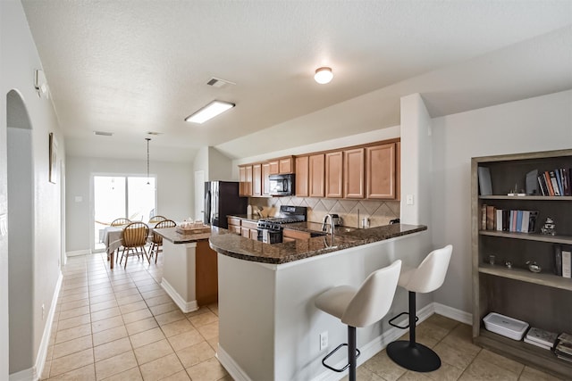 kitchen featuring backsplash, black appliances, decorative light fixtures, kitchen peninsula, and dark stone counters