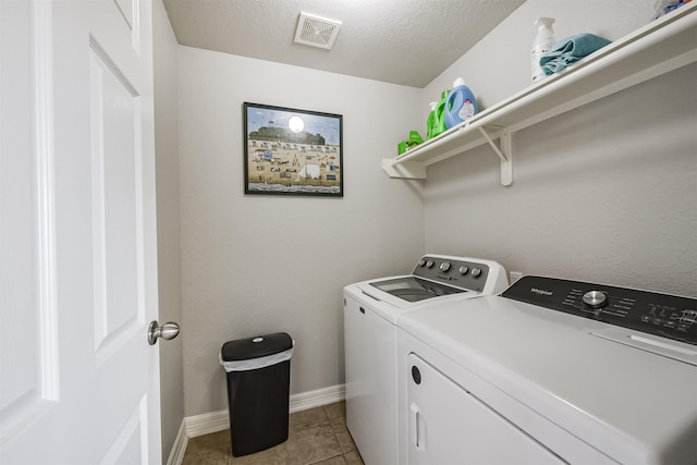 clothes washing area with independent washer and dryer, a textured ceiling, and light tile patterned floors