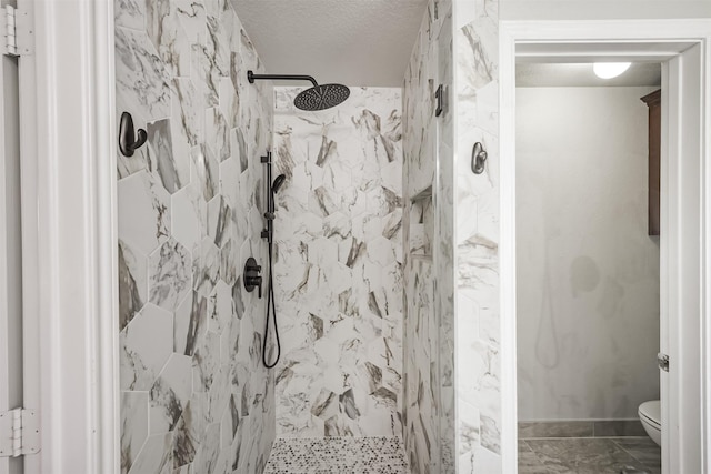 bathroom featuring a textured ceiling, toilet, and tiled shower