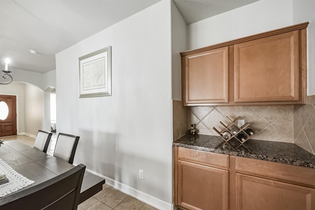 kitchen with dark stone countertops, light tile patterned floors, and decorative backsplash