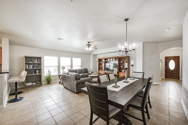 dining space with ceiling fan with notable chandelier, light tile patterned floors, and a textured ceiling