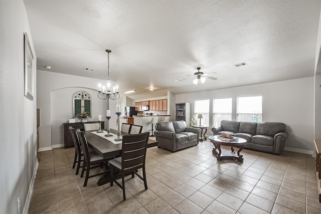 dining room featuring ceiling fan with notable chandelier, a textured ceiling, and light tile patterned flooring